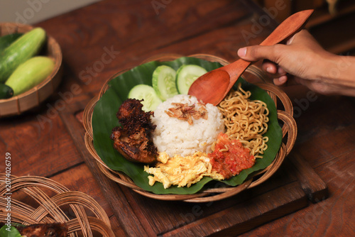 Hand holds wooden spoon over vibrant, hearty rice dish