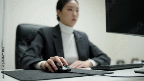 Focused Professional at Work: A Woman in Business Attire Using a Computer Mouse in a Modern Office Environment with a Concentrated Expression