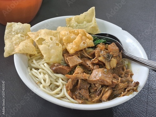 Canvastavla Delicious Indonesian chicken noodle soup with meatballs served in a bowl, topped with seasoned chicken, fresh vegetables, and savory broth