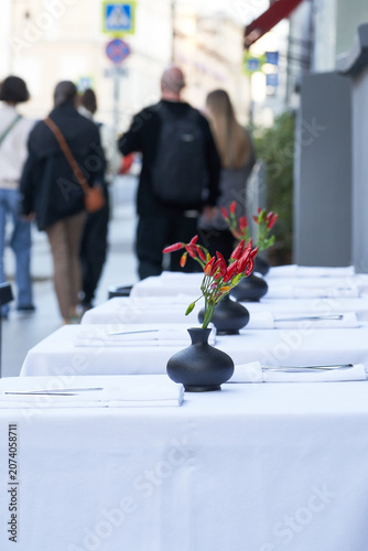 Setting tables with a white tablecloth at an outdoor cafe