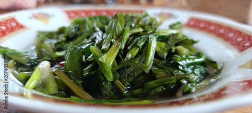 Foto Stir fried water spinach or tumis kangkung served on a traditional patterned pla