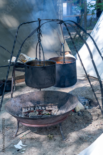 Obraz na plátně Outdoor cooking with metal cauldrons suspended over a burning campfire during re