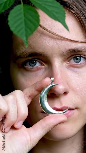 A serene portrait of a person with a silver crescent pendant