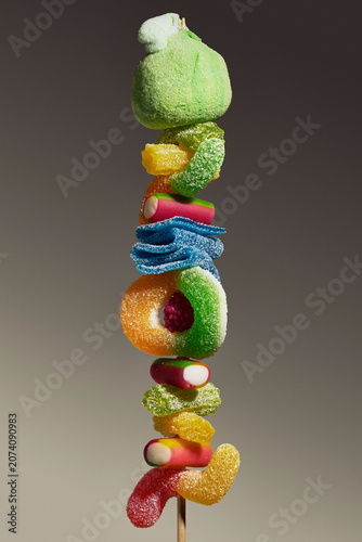 Multicolored sour jelly candy in various shapes stacked on a skewer