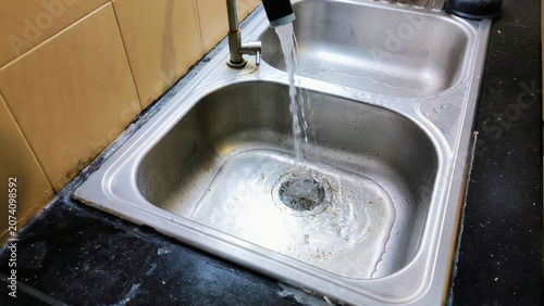 Foto A kitchen sink clogged with food scraps and dishwashing
