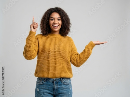 Smiling young woman pointing up and presenting with her hand