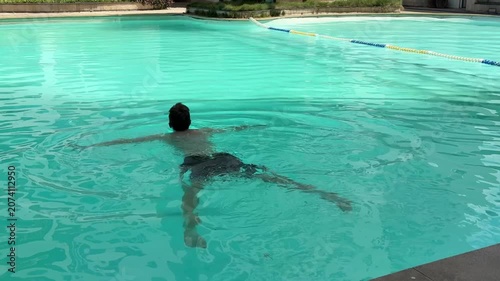 Video of a man swimming in a modern swimming pool. Healthy lifestyle and fitness concept representing physical activity, endurance, recreation and aquatic sports.