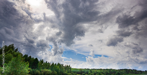 Tableau sur toile Dense clouds loom above a forested hillside