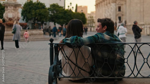 Obraz na płótnie Couple Sitting On Bench In Plaza At Dusk
