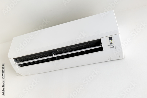 Wall-mounted split air conditioner unit on white wall, indoor climate control.