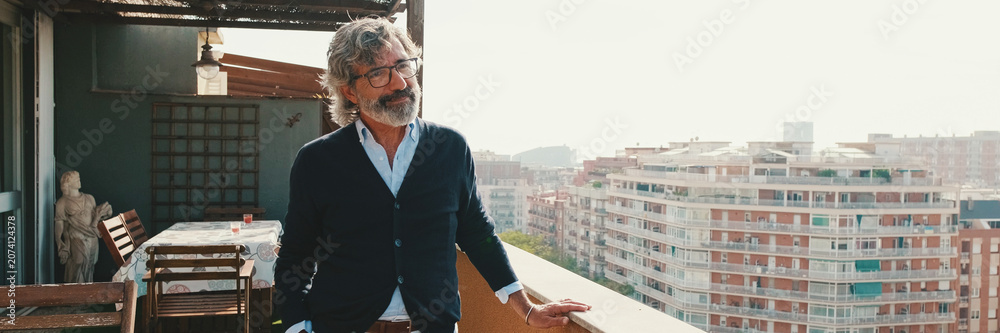 Fototapeta premium Senier enjoys the view standing on the balcony. Panoramic