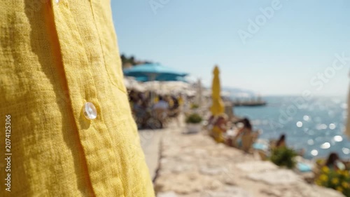 A Vibrant Yellow Shirt with a Button Near a Scenic Seaside Walkway, Capturing a Laid-Back Atmosphere Under the Bright Summer Sun by the Shoreline