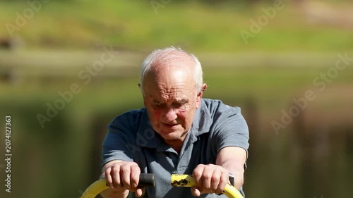 senior man exercising outdoors on an exercise machine
