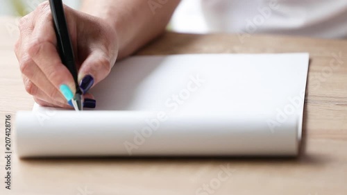 Close-up of elegant young woman's hands with stylish painted nails writing in notebook with pen, creative journaling lifestyle concept