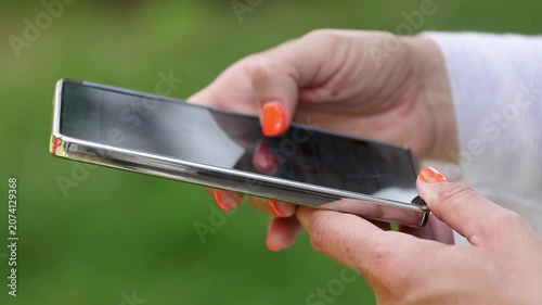 Close-up of a woman's finger scrolling on a smartphone screen, browsing social media, apps, and online content. Modern lifestyle, technology, and digital communication concept