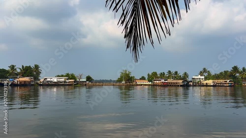Traditional houseboats docked along the tranquil backwaters of Kerala, surrounded by lush tropical scenery