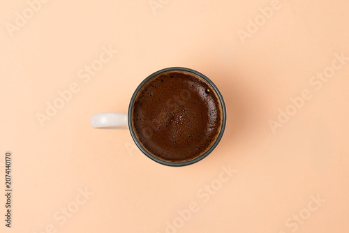 A cup filled with frothy Turkish coffee on a colorful background.