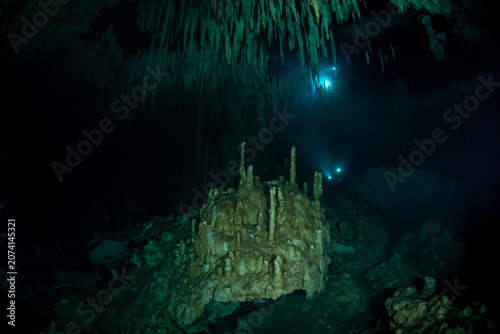 Foto Dark cenote cave chamber illuminated by diver torch beams in Mexico