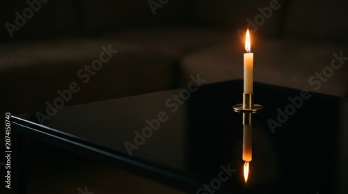 Single candle burns on a glossy black surface with a clear flame reflection, dark surroundings, and simple Halloween atmosphere for moody seasonal greetings, candle cards, and quiet invitations.