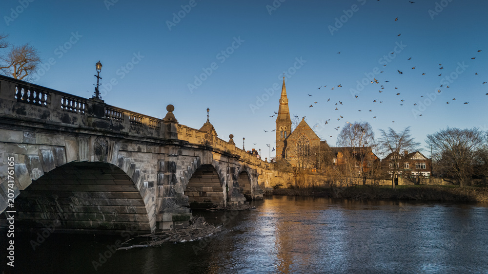 Fototapeta premium Pigeons in Flight Over English Bridge and River Severn with Church Spire, Shrewsbury