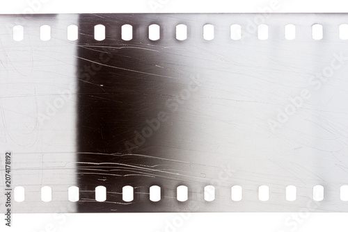 Dusty and grungy 35mm film texture or surface. Perforated scratched camera film isolated on white background.