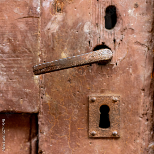 Rusty antique iron door handle with vintage keyhole