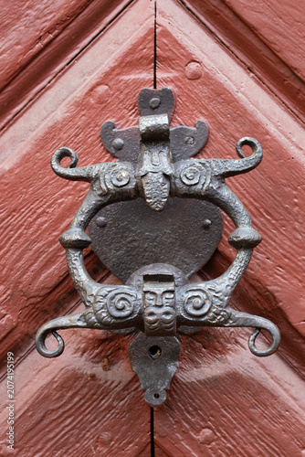 Ornate antique iron door knocker with decorative masks