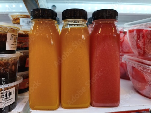 Fresh Juices in Transparent Bottles and Food Containers in Refrigerator