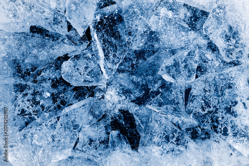 Broken ice. Crushed textured ice with cracks on a black background, in cold blue tones.