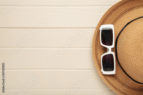 Photos A stylish straw hat and white sunglasses on light background.