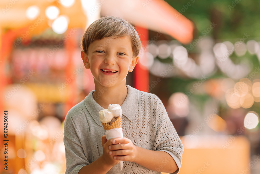 Fototapeta premium Happy boy eats ice cream in the park in summer
