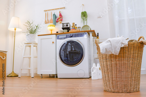 Beautiful housewife is busy daily chores preparing laundry cleaning clothes using large water saving washing machine that allows wash large quantities laundry quickly and efficiently speeding up work.
