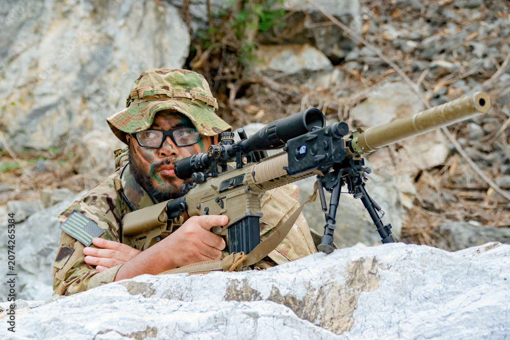 Fototapeta premium Snipers in camouflage uniforms conceal themselves behind rocks their rifles ready to fire at the enemy during combat.
