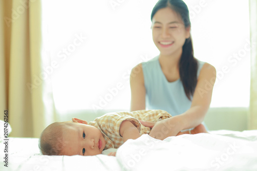 Bild auf Leinwand Heartwarming moment depicting the love and bond between mother and her eight month old son on a comfortable bed the young mother lovingly caresses her baby and the warmth family