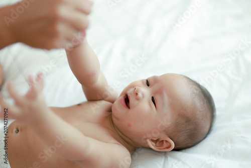 Tableau sur toile Adorable 7 month old baby was lying on the bed crying adorably while playing with his mother