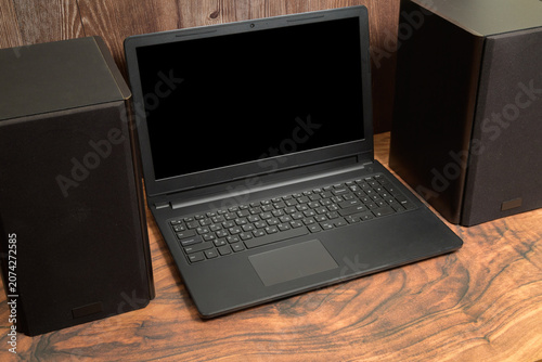 black laptop between two large musical speakers