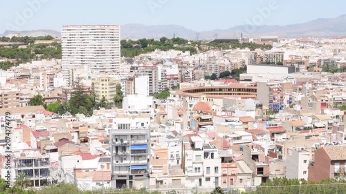A cityscape view of Alicante, Spain, showcasing dense architecture and mountains in the background during a camera panning
