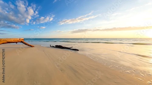 Beautiful tropical beach with golden sunset, white sand, and calm ocean waves