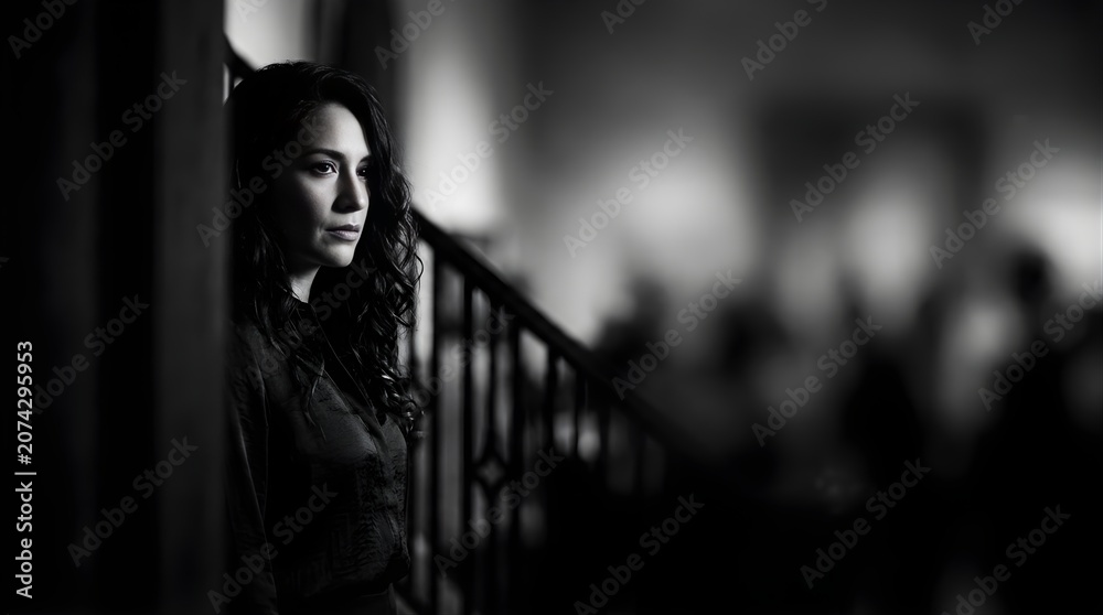 Fototapeta premium Portrait of a pensive woman standing near a staircase in black and white