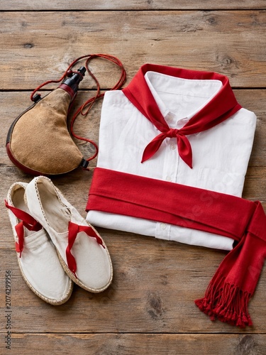 San Fermin festival outfit with white shirt, red bandana, red sash, espadrilles and wineskin.