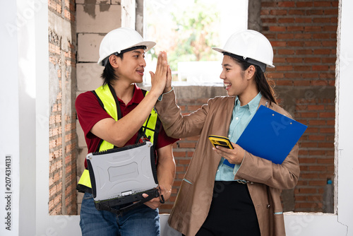 Asia construction workers high-fiving with female architect on site
