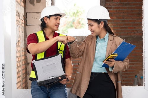 Construction worker and female architect fist bumping on site