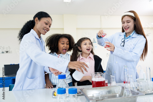 Very happy two female teachers and two young girls conducting a science experiment in a laboratory