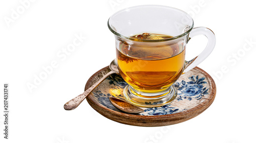 Photos Glass cup of amber tea on decorative saucer with spoon