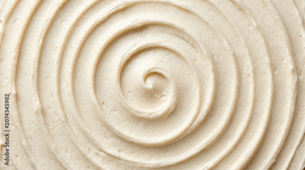 Fototapeta premium Close up concentric swirl of vanilla buttercream frosting with smooth ridges and creamy texture on neutral surface, food detail and pattern study