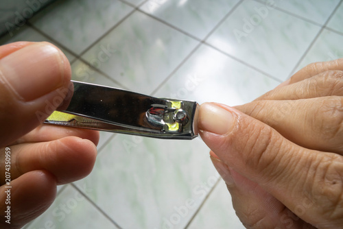 Person cutting long fingernails using metal steel nail clipper tool for personal hygiene care