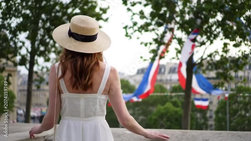 Woman in hat viewing Paris city with French flags.
