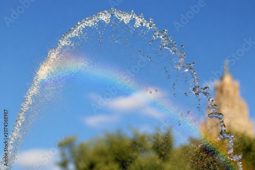 Cuadro en lienzo A fountain's water jet arching against a blue sky with sunlight creating glints