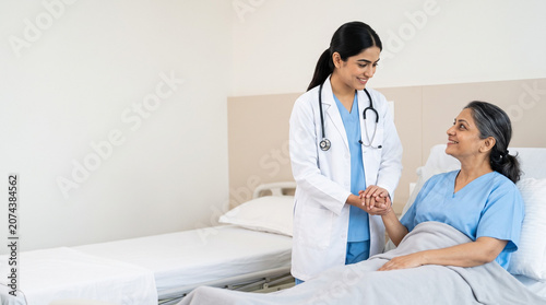 attractive indian female doctor holding hands with middle aged patient in hospital room representing compassionate healthcare and recovery support