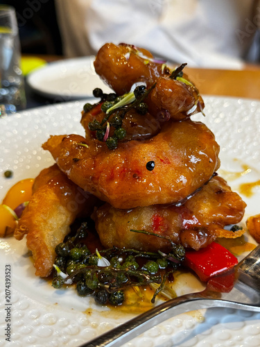 glazed vegetarian shrimp stacked with herbs and vegetables on white plate